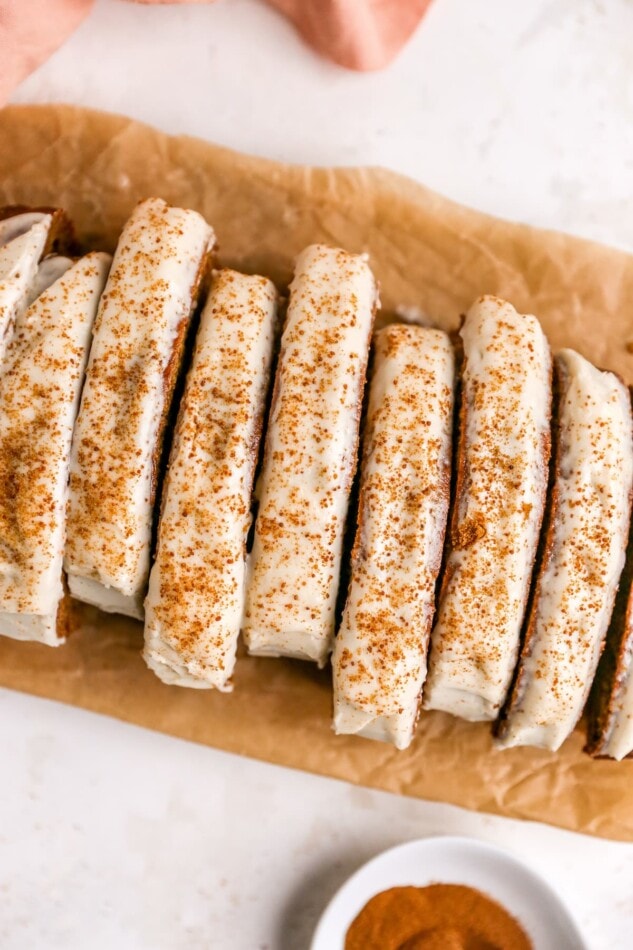 A gingerbread loaf with maple cream cheese frosting that has been sliced.