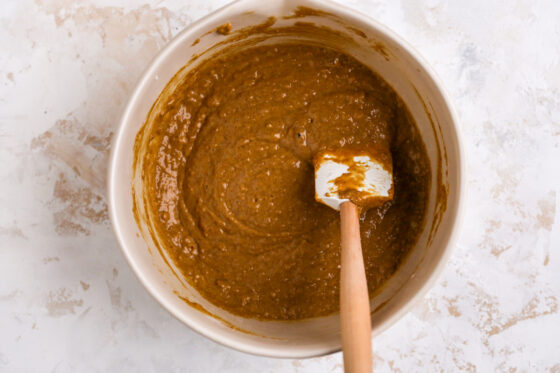 Gingerbread loaf batter in a mixing bowl. A spatula rests in the bowl.