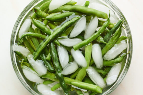 Blanched green beans in an ice water bath.