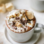 A mug of healthy hot cocoa. It has been topped with whipped cream and toasted marshmallows.