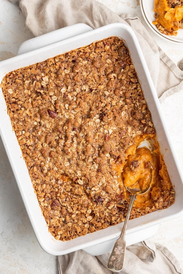 Healthy sweet potato casserole in a baking dish with a spoon.