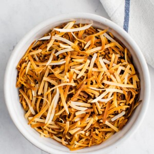 An overhead photo looking at a bowl containing toasted shredded coconut.