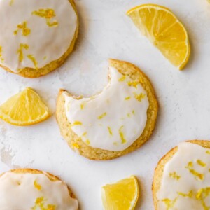 An overhead photo looking at lemon almond flour cookies scattered on a table top. The center cookie has a bite removed.