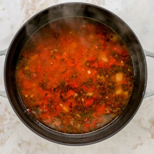 A large pot with veggies for minestrone soup, vegetable broth has just been added to the pot.