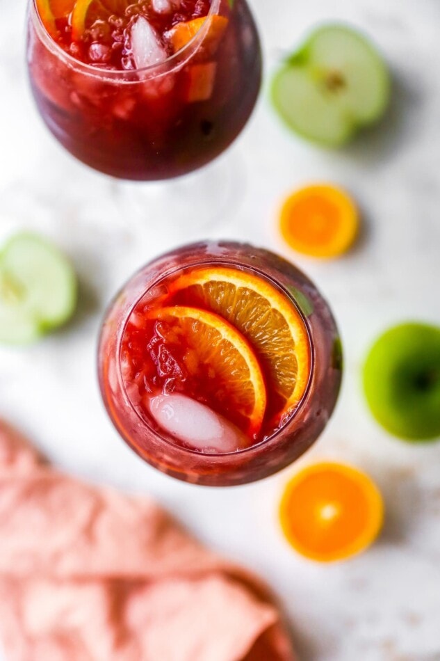 Overhead view of a glass of red wine sangria garnished with 2 orange slices.