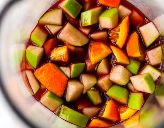 An overhead view of red wine sangria. You can see chunks of chopped apple, orange and lemon.