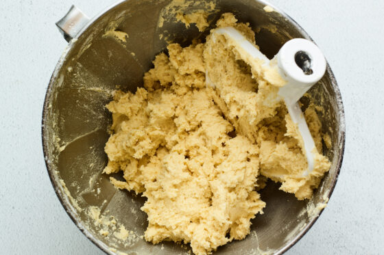 Rugelach dough freshly mixed in a mixing bowl. The mixer attachment is in the bowl.