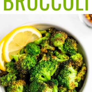 An overhead view of a small bowl of air fryer broccoli. There are two lemon slices resting in the bowl as a garnish.