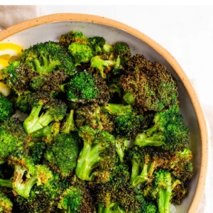 An overhead view of a bowl of air fryer broccoli, the bowl is resting on a linen dish cloth.