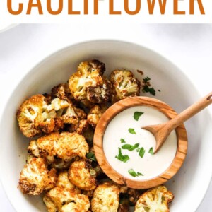 An overhead photo looking down at a bowl of air fryer cauliflower. There is a small wooden bowl inside the larger bowl containing ranch dipping sauce.