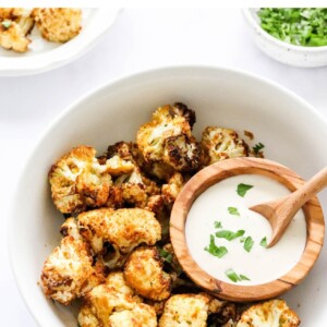 An overhead photo looking down at a bowl of air fryer cauliflower. There is a small wooden bowl inside the larger bowl containing ranch dipping sauce.