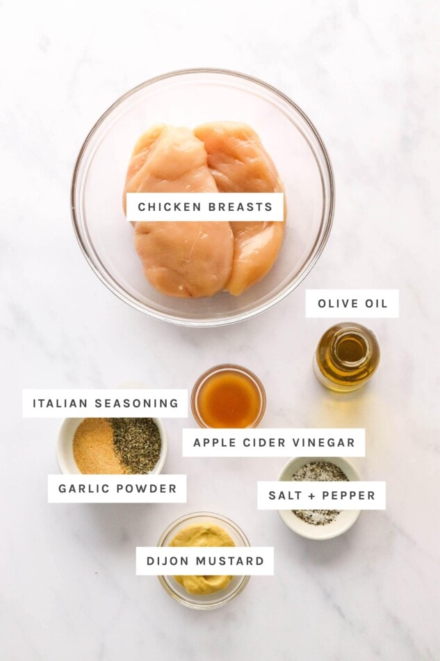 Ingredients measured out to make air fryer chicken: chicken breasts, olive oil, apple cider vinegar, Italian seasoning, garlic powder, salt, pepper and dijon mustard.
