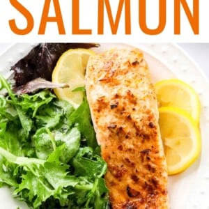 Overhead photo of a plate with filet of air fryer salmon served with leafy greens and lemon slices.