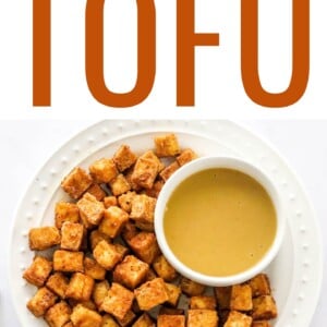 An overhead photo of a plate of air fried tofu with a ramekin of dipping sauce. A gold fork is next to the plate.
