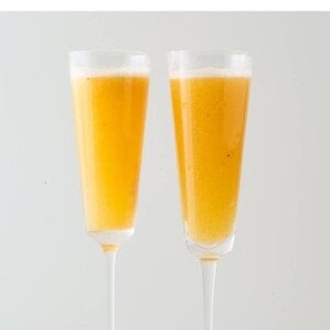 Two champagne flutes containing an easy peach Bellini.