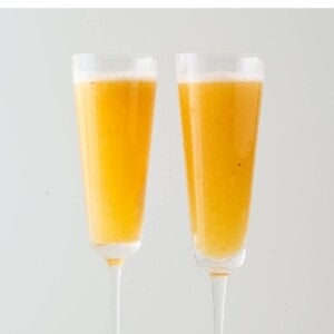 Two champagne flutes containing an easy peach Bellini.