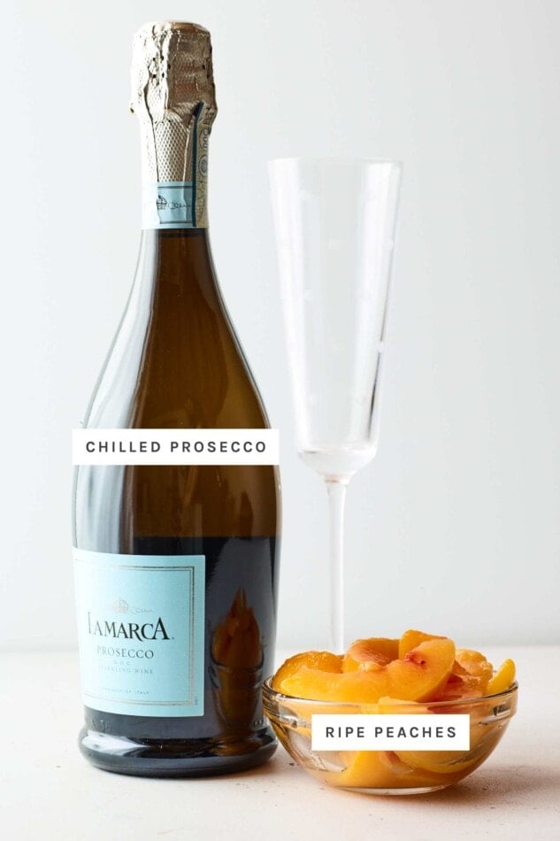 Ingredients to make a bellini: chilled bottle of prosecco, peach slices and a glass.