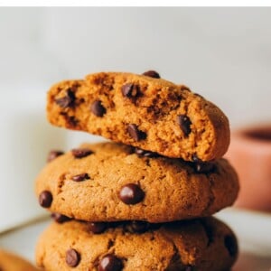 Stack of three chocolate chip cookies. The top is broken in half.