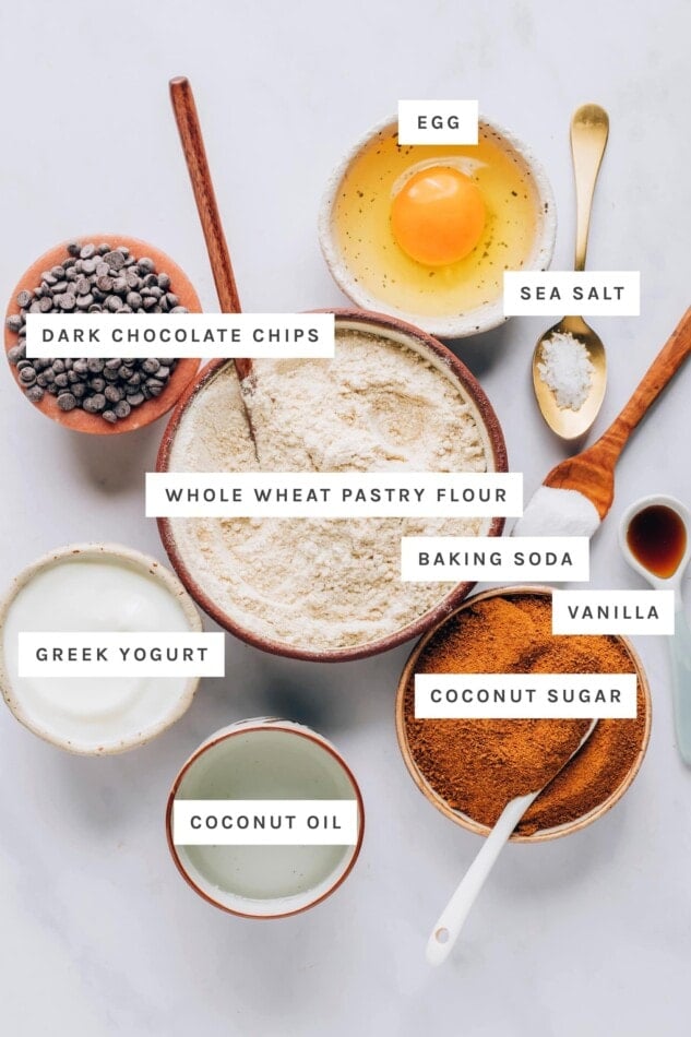Ingredients measured out to make healthy chocolate chip cookies: egg, dark chocolate chips, sea salt, whole wheat pastry flour, baking soda, vanilla, Greek yogurt, coconut sugar and coconut oil.