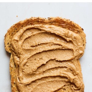 A slice of toast with cinnamon peanut butter spread on top.