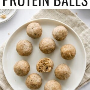 An overhead and closeup photo looking down on 10 coconut protein balls on a plate. The center ball has a bite taken out of it. The plate is on a khaki dish cloth.