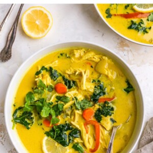 Two bowls of detox soup. There are two spoons nearby and a small dish of fresh cilantro.