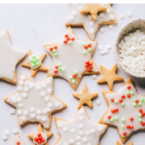 Various sized star shaped healthy sugar cookies scattered around a countertop. Some of the cookies have been decorated and some are plain.