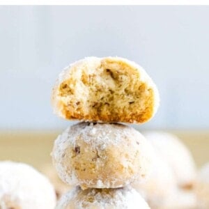 Stack of three snowball cookies. The top has a bite taken out of it.