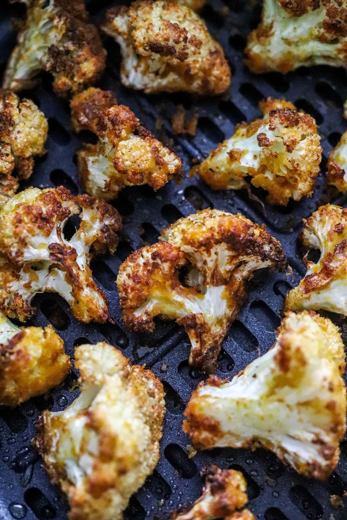 A close up photo of air fryer cauliflower in an air fryer basket.