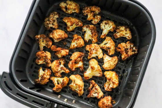 An air fryer basket containing air fried cauliflower.