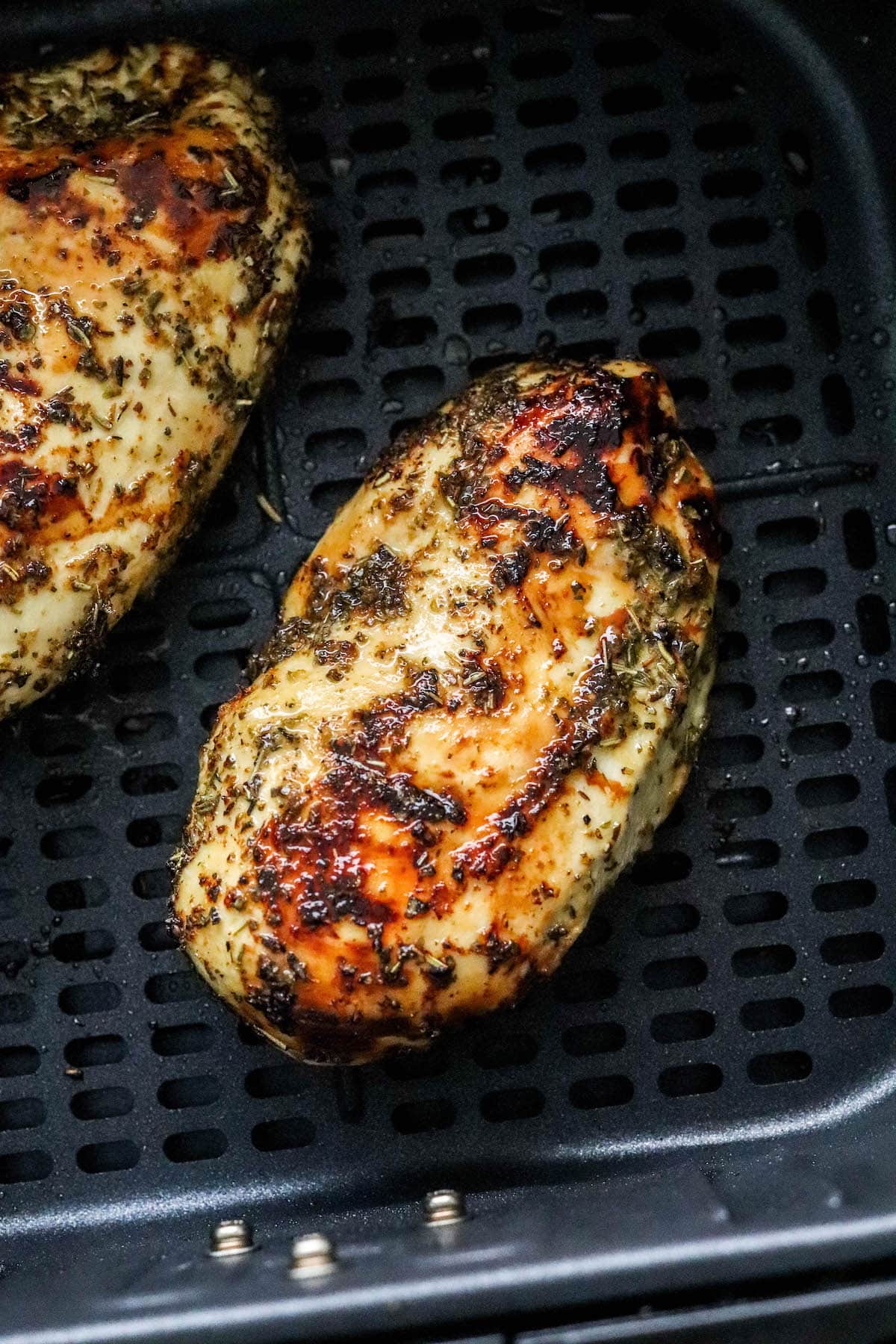 A close up of an air fried chicken breast in an air fryer basket.