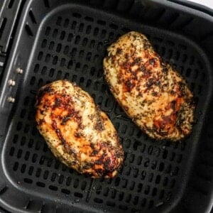 Two air fried chicken breast in an air fryer basket.
