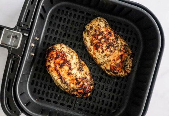 Two air fried chicken breast in an air fryer basket.