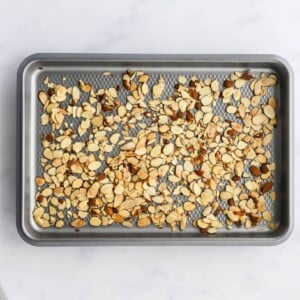 Roasted slivered almonds scattered on a baking sheet.
