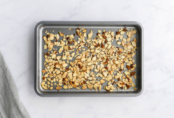 Roasted slivered almonds scattered on a baking sheet.