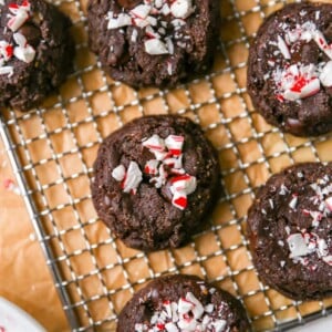 A close up overhead photo looking down at chocolate peppermint cookies on a wire cooling rack on top of brown parchment paper.