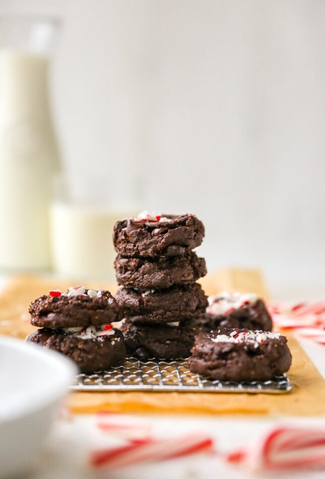 Stacks of chocolate peppermint cookies on a wire cooling rack on top of brown parchment paper.