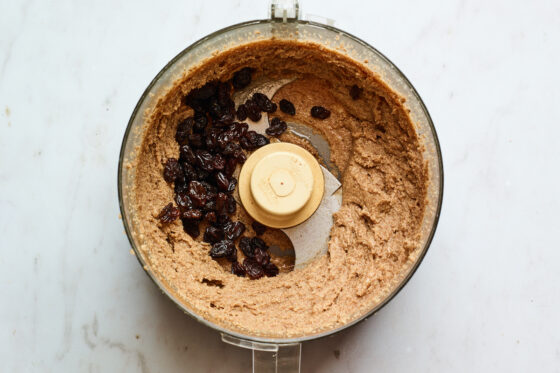 Raisins added to a food processor containing almond butter.