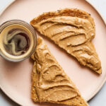 A plate a slice of toast cut in half spread with creamy cinnamon peanut butter.