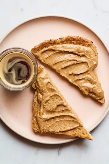 A plate a slice of toast cut in half spread with creamy cinnamon peanut butter.
