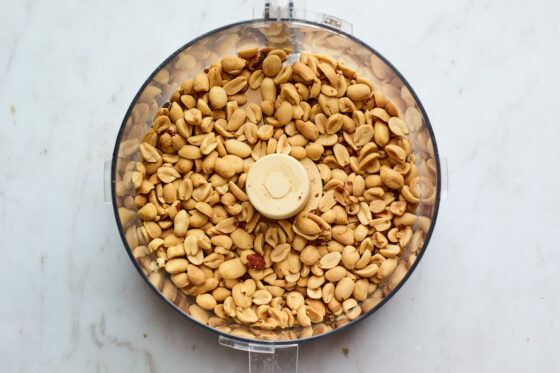 A food processor containing whole peanuts.