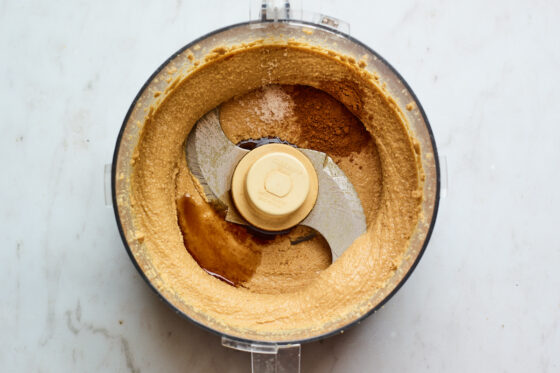 Cinnamon and vanilla added to freshly processed peanuts in a food processor.