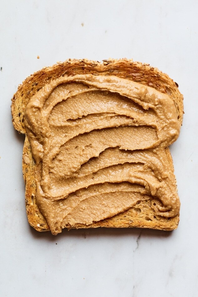 A slice of toast with cinnamon peanut butter spread on top.