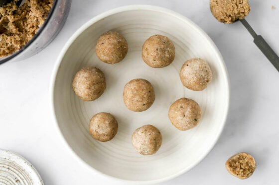 A tablespoon is used to scoop proportionate amounts of mixture out that are then shaped into balls to create coconut protein balls.