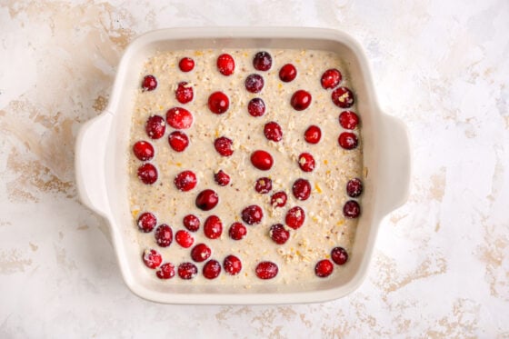 A baking dish with cranberry orange oatmeal mixture, topped with whole cranberries.