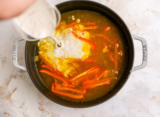 Coconut milk being added to the pot of ingredients.