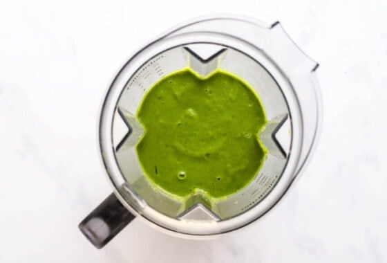 Green detox smoothie ingredients blended in a blender.