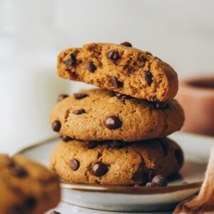 Three healthy chocolate chip cookies stacked on top of each other. The top cookie has been cut in half, exposing the inside.