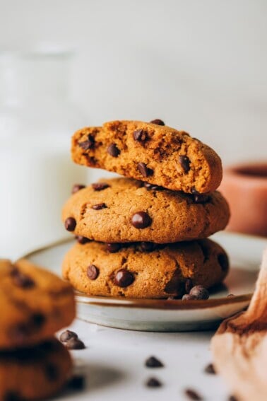 Three healthy chocolate chip cookies stacked on top of each other. The top cookie has been cut in half, exposing the inside.