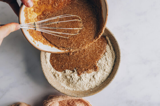 Wet ingredients being poured into a mixing bowl with dry ingredients.